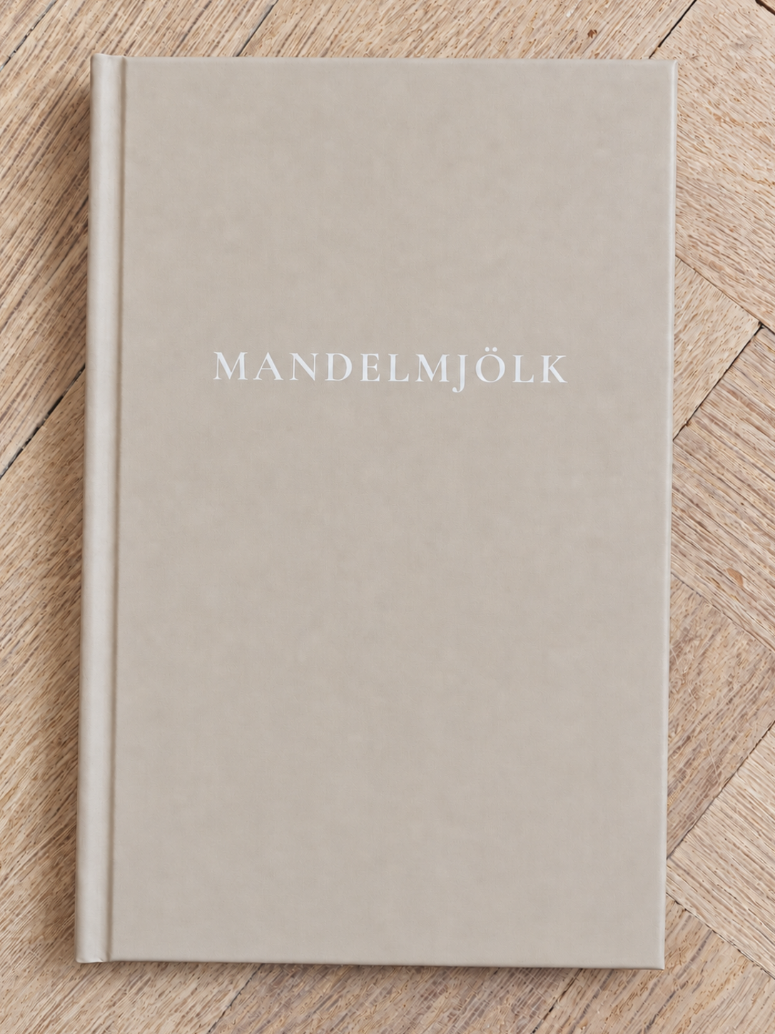 Beige Mandelmjölk anteckningsbok på ljus fiskbensparkett