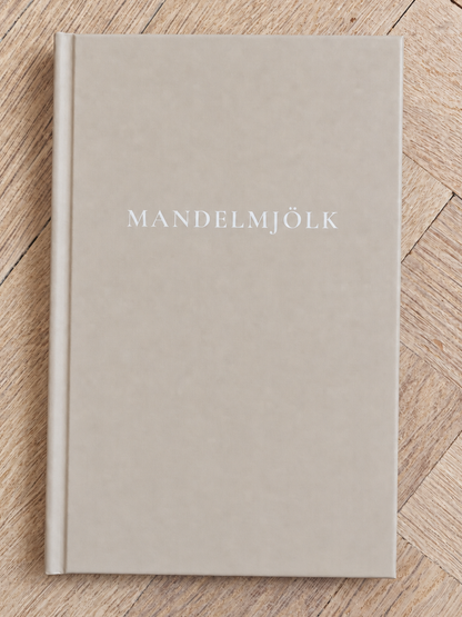 Beige Mandelmjölk anteckningsbok på ljus fiskbensparkett