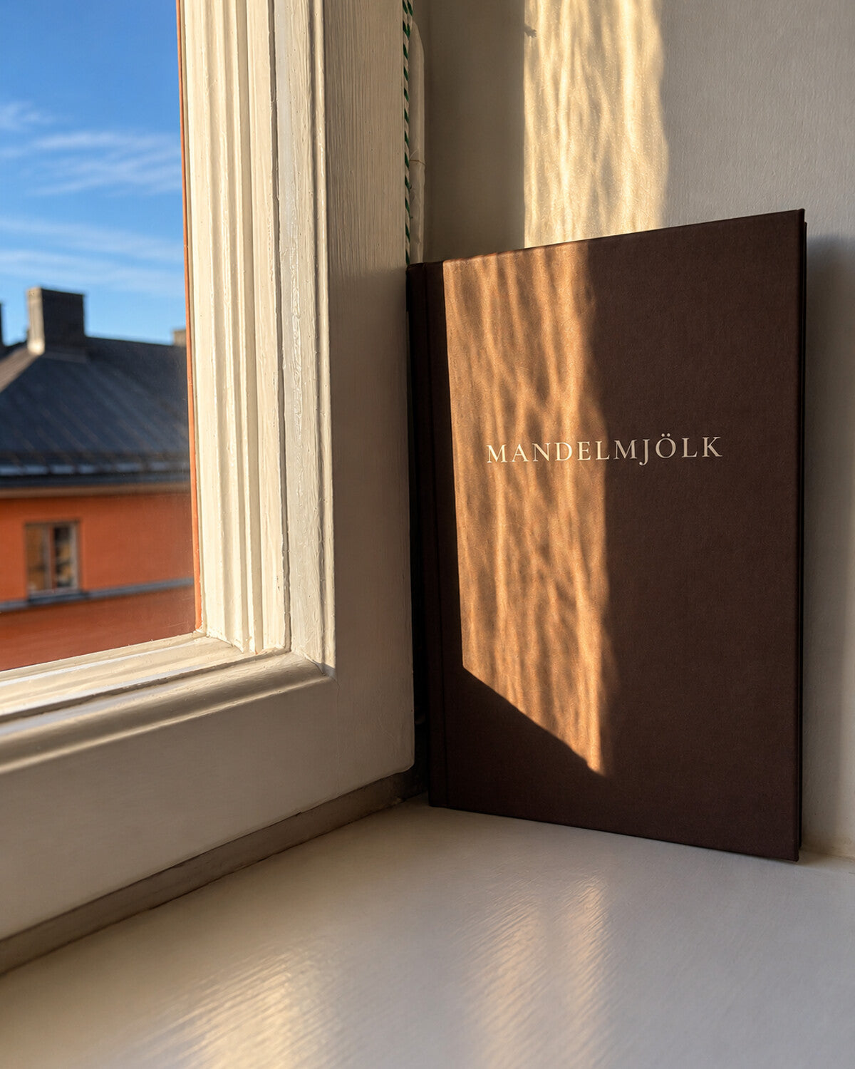 Mandelmjölk mörkbrun anteckningsbok i varmt solljus vid ett fönster