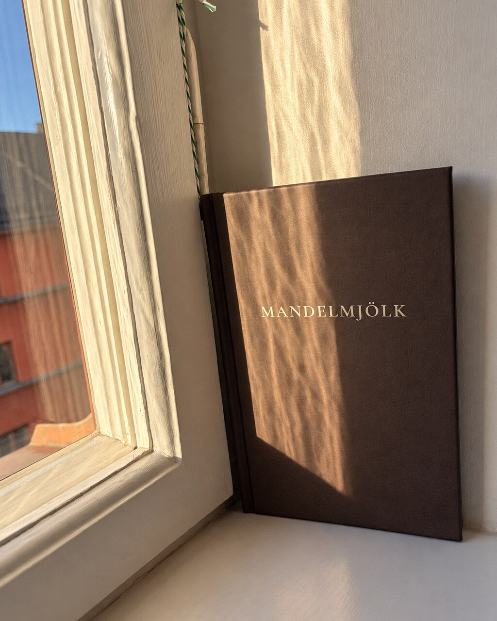 Mörkbrun Mandelmjölk anteckningsbok i varmt mönstrat fönsterljus