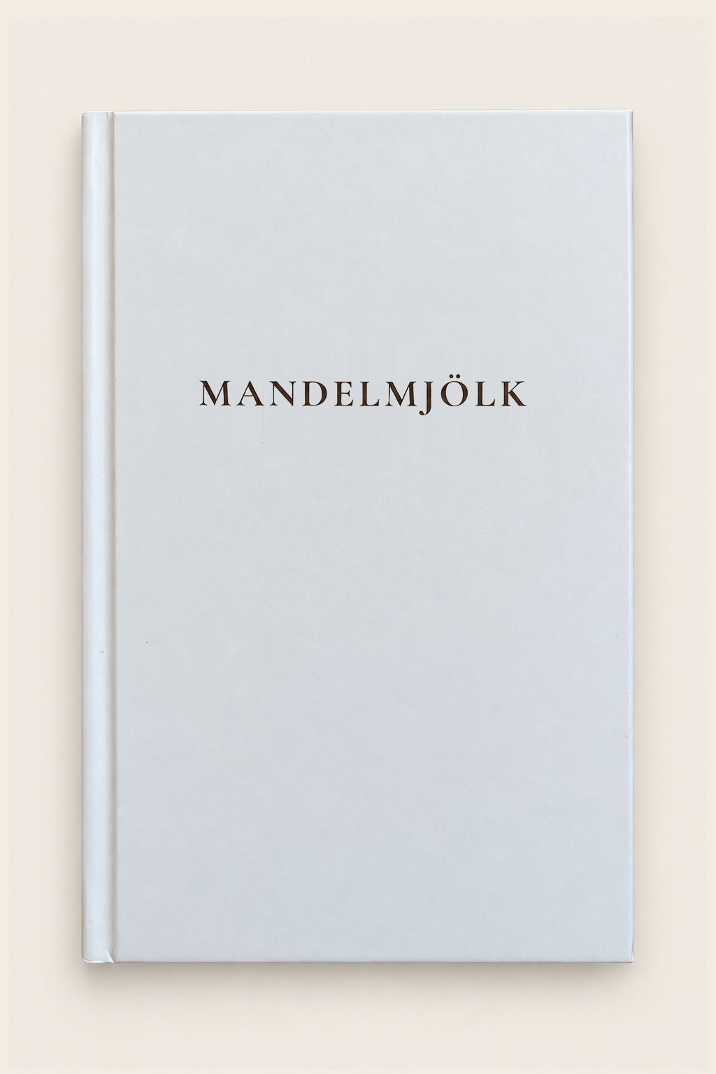 Mandelmjölk anteckningsbok med ljust omslag och mörkbrun titel mot beige bakgrund