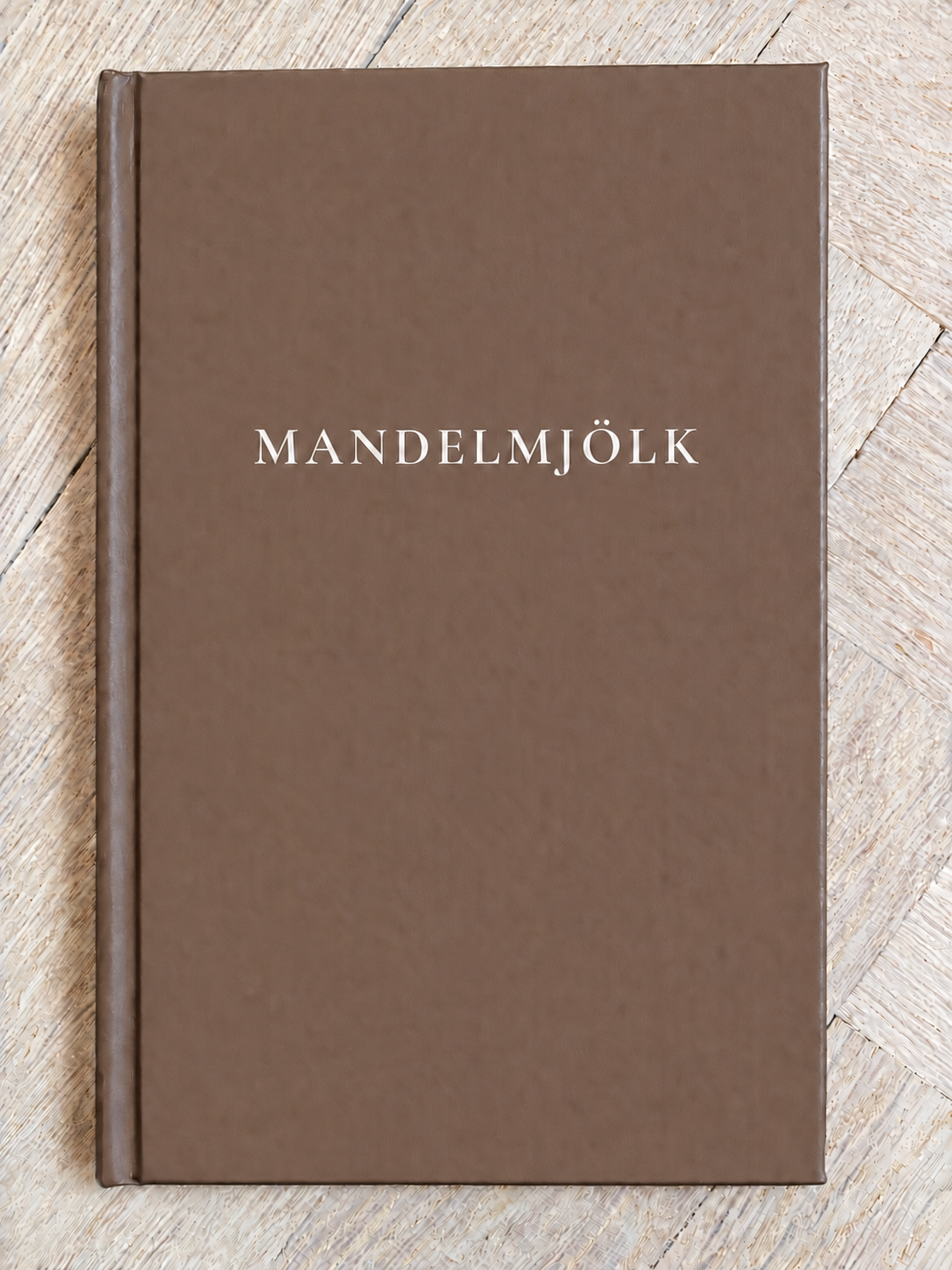 Mörkbrun Mandelmjölk anteckningsbok på ljus fiskbensparkett